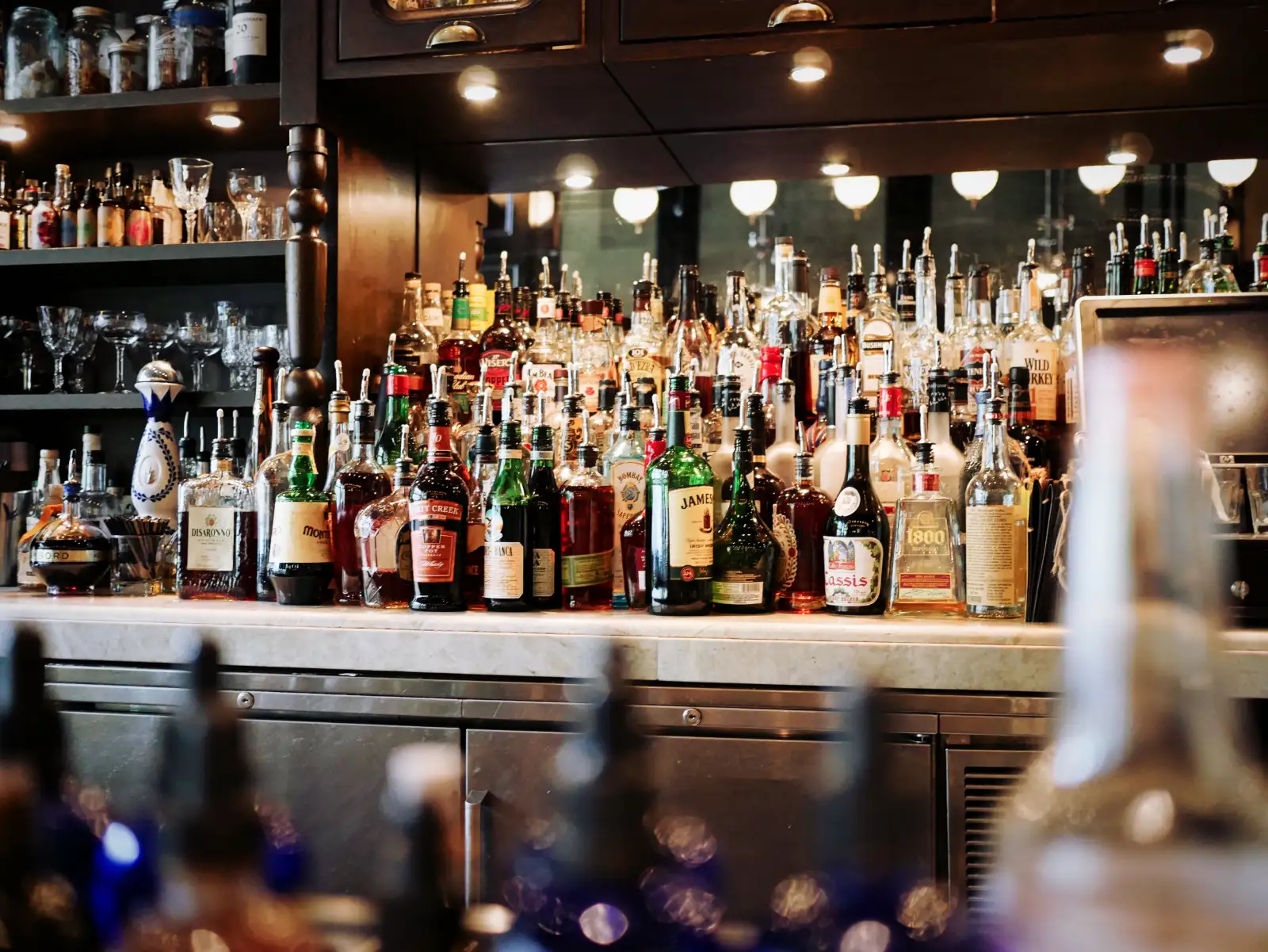 Rows of bottles on lit shelves behind a bar